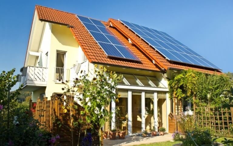 Huis met zonnebloemen en zonnepanelen