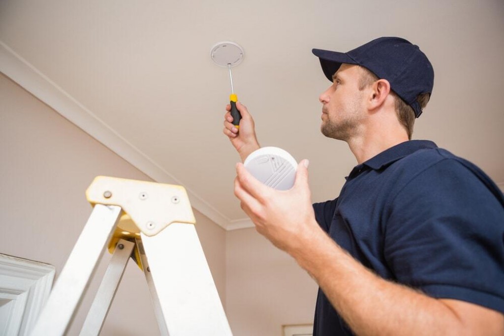 Homme installe un détecteur de fumée